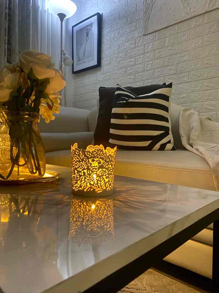 White and gold toned living room featuring white sofa, gold tray, and cozy candlelight ambiance