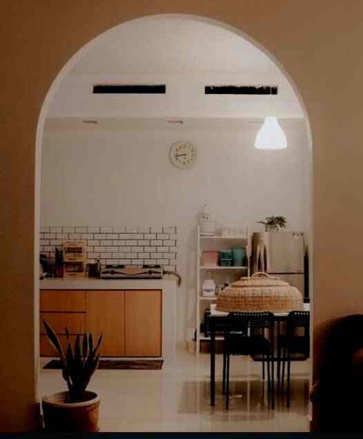 A modern and cozy kitchen and dining room featuring white walls, wood tones, and a pendant light above the dining table