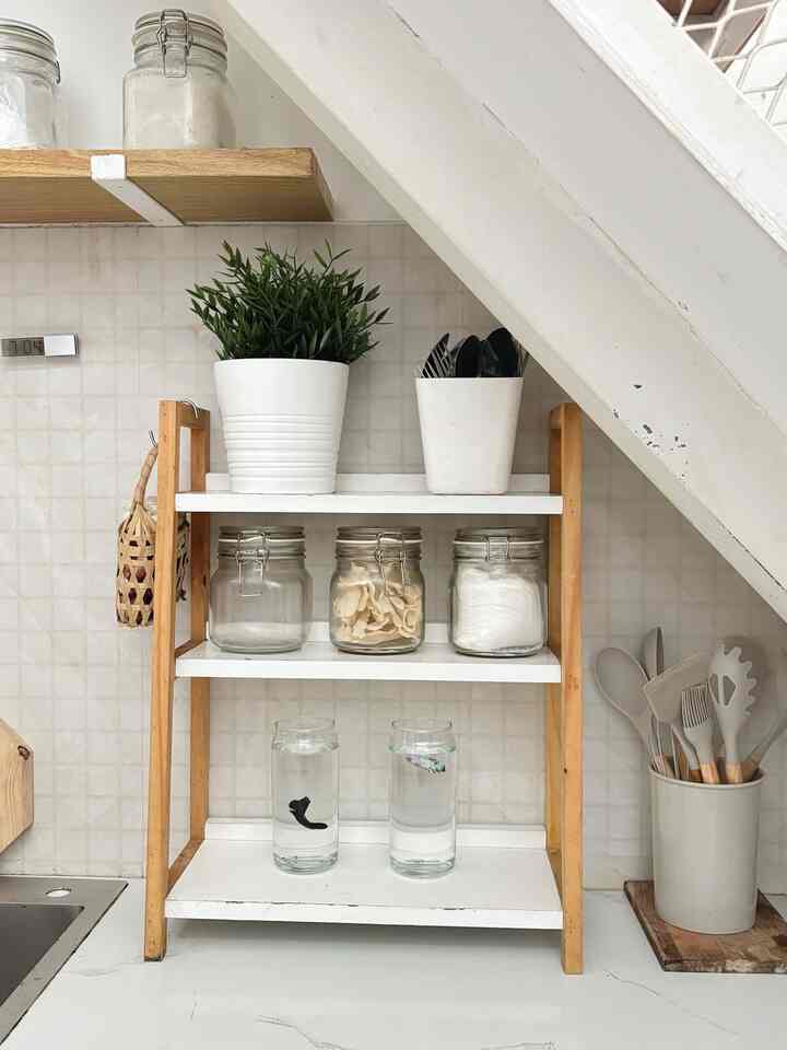 White and wood-tone kitchen featuring shelves neatly organized with jars, utensils, and decor creating a cozy atmosphere