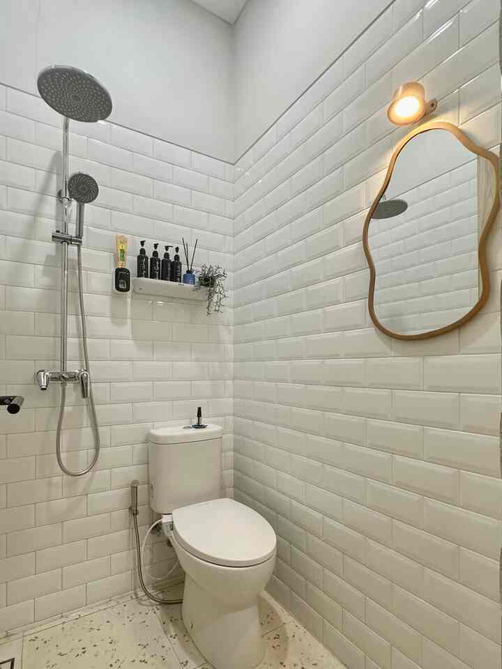 Minimal bathroom with white tiles and abstract mirror creating an airy, spacious feel