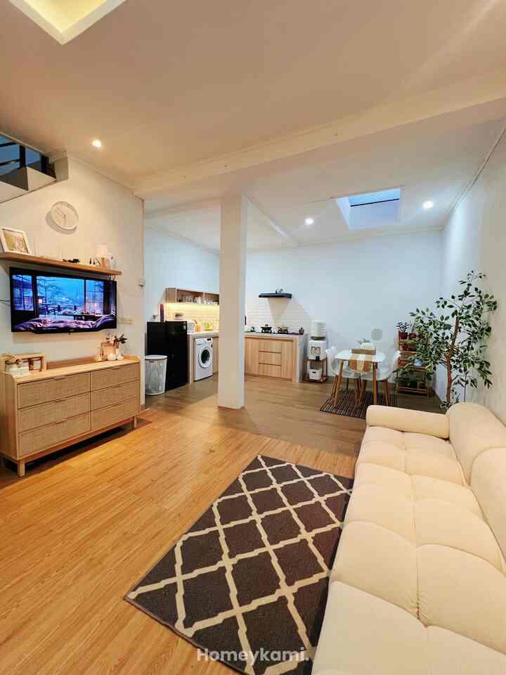 White walls and natural brown wood flooring with sofa and carpet in a modern living room and kitchen space