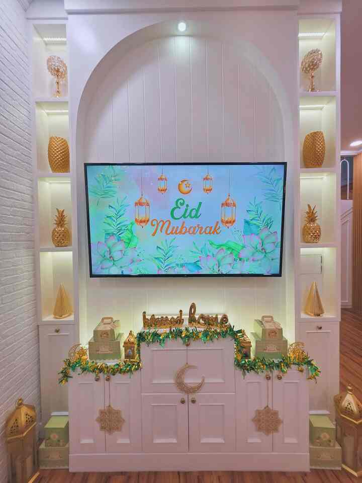 White and gold-toned living room wall featuring a TV and gold decorative items, creating a festive home party atmosphere