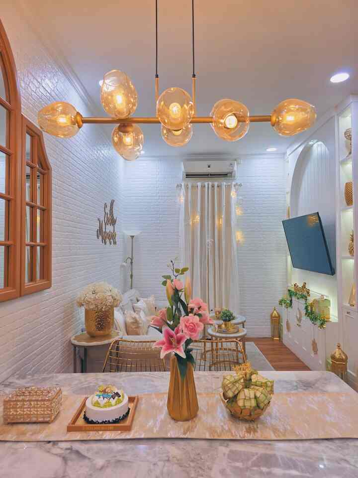 White and gold toned living room featuring pendant lighting and decorative items, creating an elegant and warm atmosphere