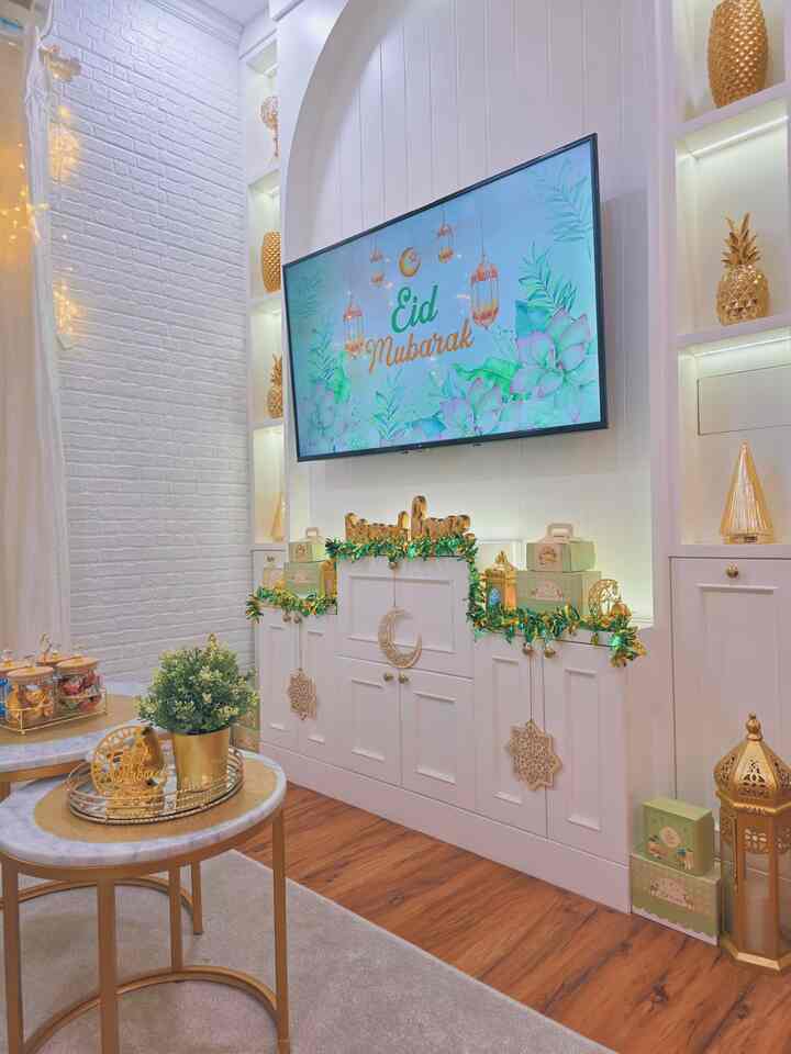 White and gold toned living room featuring wall-mounted TV and golden festive decorations with cozy atmosphere