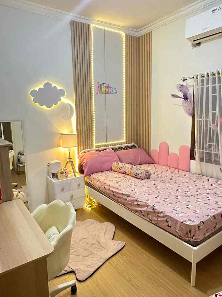 Pink and brown toned kids' room featuring bed, desk, nightstand, and wall lighting creating a cozy atmosphere