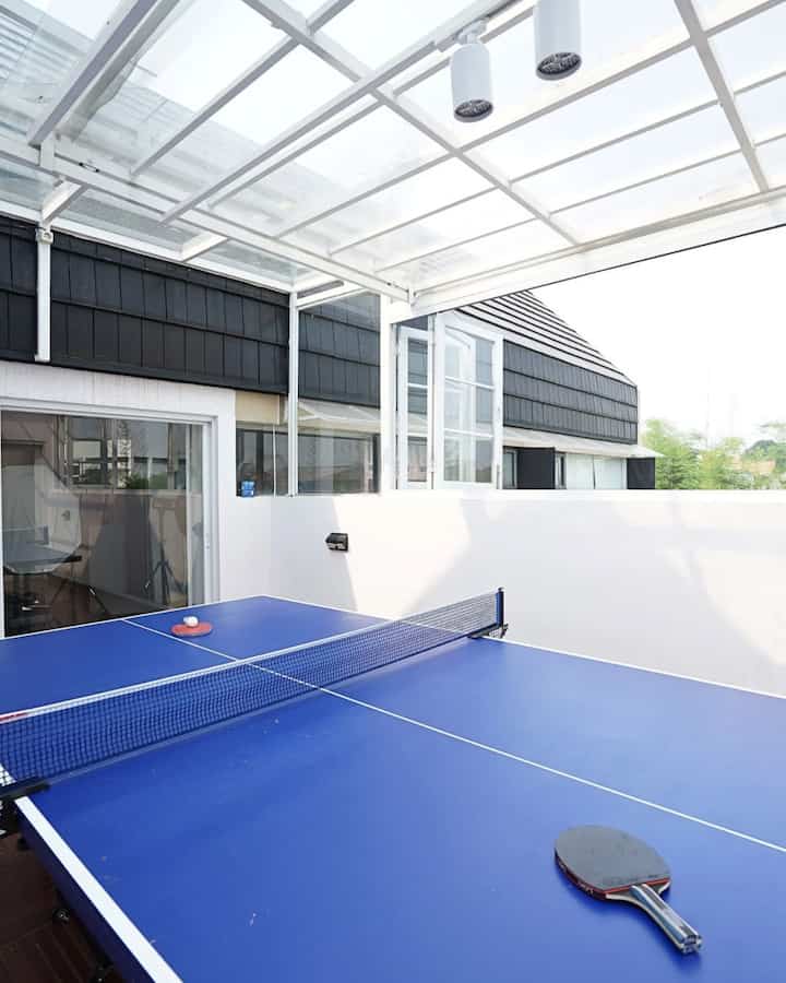 The 2nd floor of our house consists of a home gym, a rooftop with a ping pong table, and a laundry room.

On the roof, a glass canopy is installed that can be opened and closed for air circulation. When it rains, the canopy can be closed to keep the ping pong table dry.

We want the whole house to be active in exercising, lifting weights in the home gym, but also being able to move while having fun playing ping pong.

#rooftoparea #homegym #kanopiputih #kanopikaca #mejapingpong

