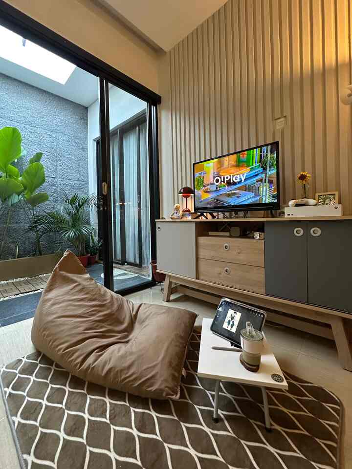 Natural-toned living room featuring a large beige bean bag, cabinet, and plants, creating a cozy atmosphere