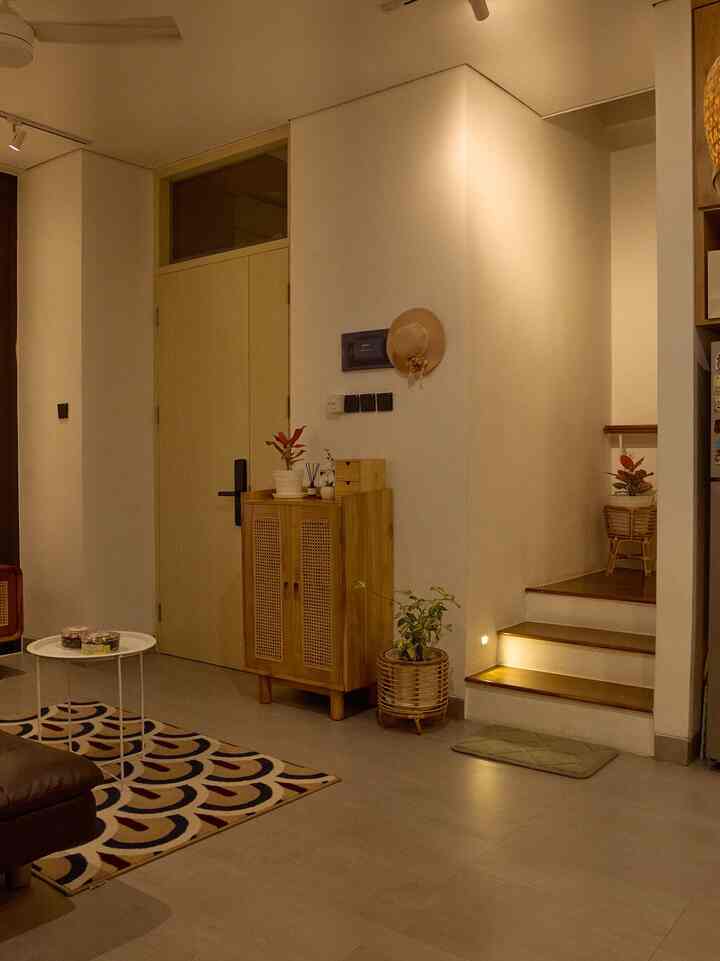 Beige and wood tone living and entrance area featuring rattan cabinet and plants, creating a natural and warm atmosphere