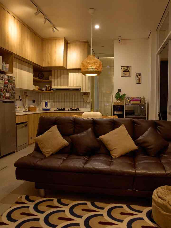 Warm brown and wood tone living room and kitchen featuring a dark brown sofa and pendant light with cozy atmosphere