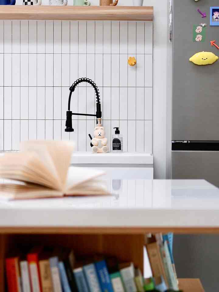 Modern kitchen with white wall tiles and black faucet, clean white countertop and sink area