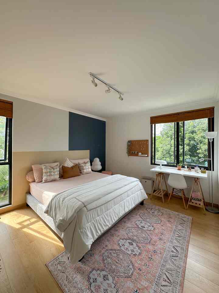Natural kids' bedroom with warm wood flooring, pink bedding, large windows allowing abundant natural light