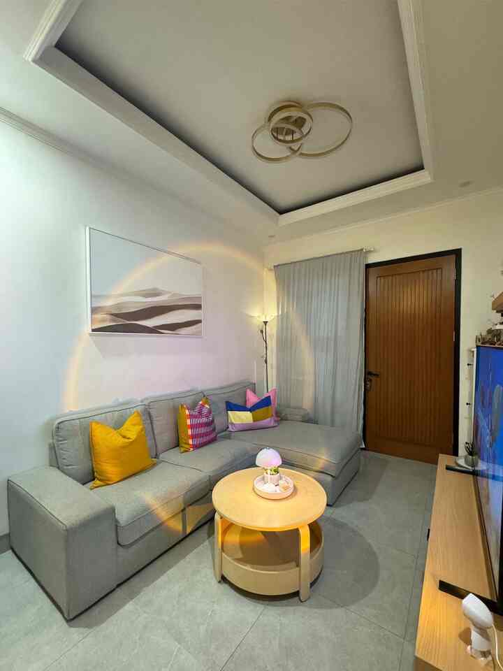 Bright modern living room featuring a gray sofa and light brown round coffee table with minimal decor