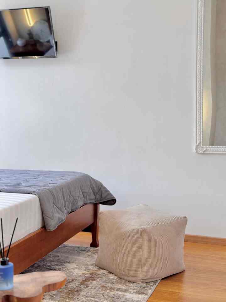 Simple bedroom space with beige bean bag and brown wooden bed
