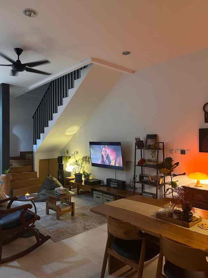 Bright white-walled living and dining room featuring wood tone furniture, warm lighting, and a TV stand creating a cozy atmosphere