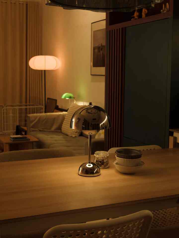 Warm wood tone and beige living-dining room featuring a silver table lamp centrally placed on the dining table, creating cozy ambiance