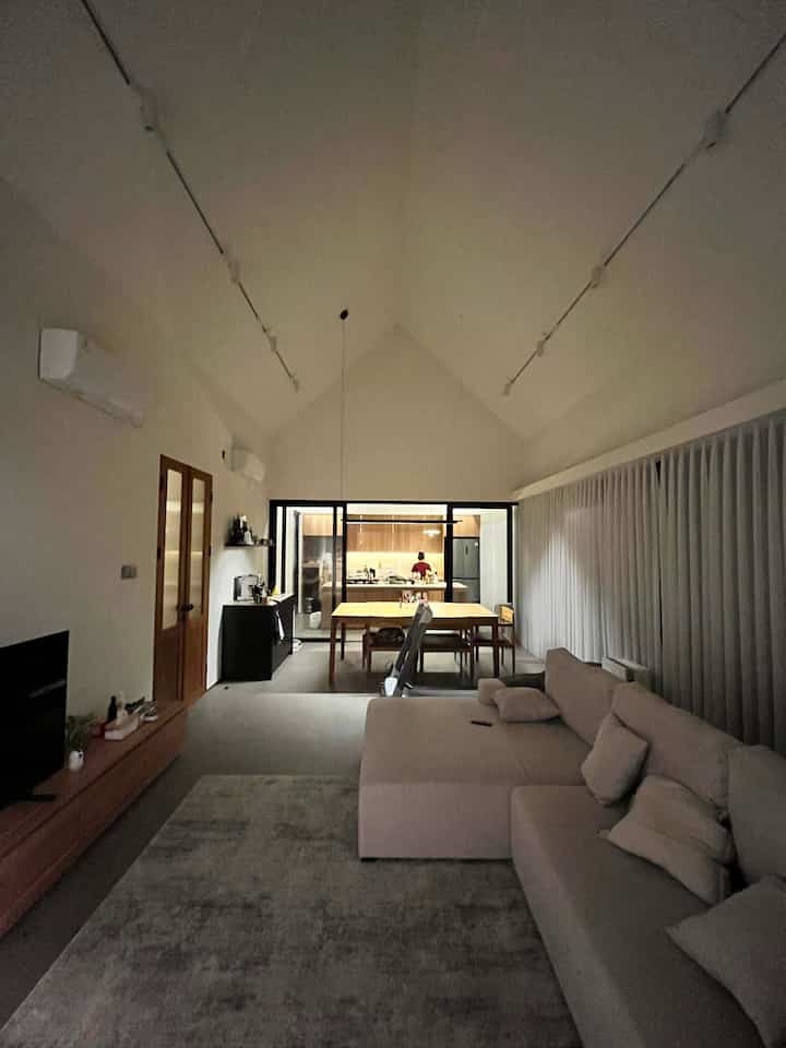 Cozy open-plan living room, dining area, and kitchen featuring warm beige and wood tones with ambient warm lighting
