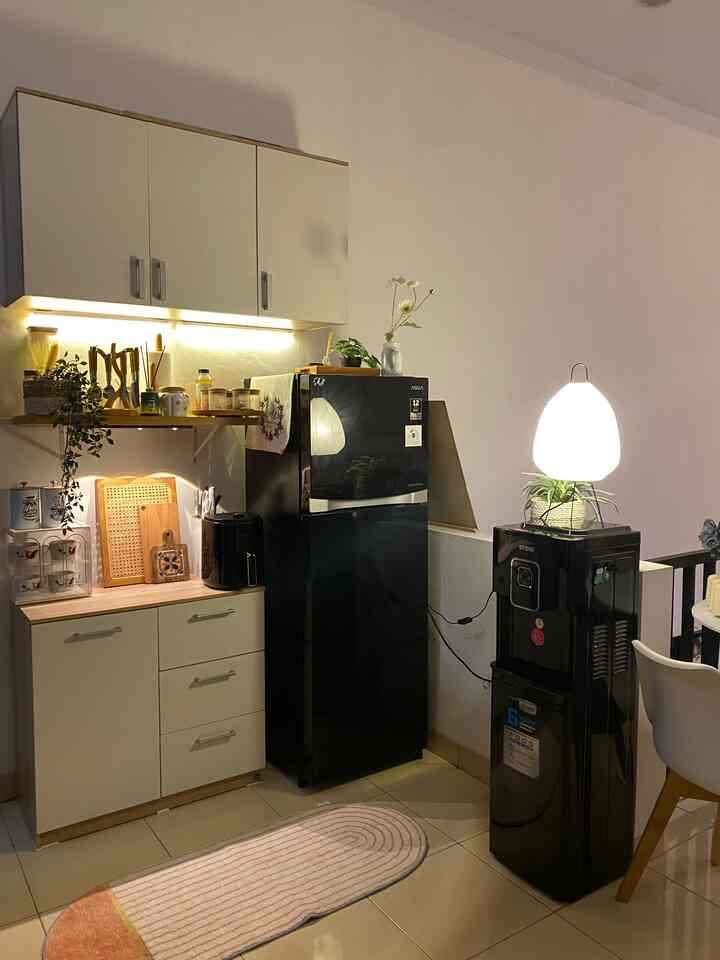 Cozy kitchen space with white walls and cabinetry, black refrigerator and water dispenser arranged neatly