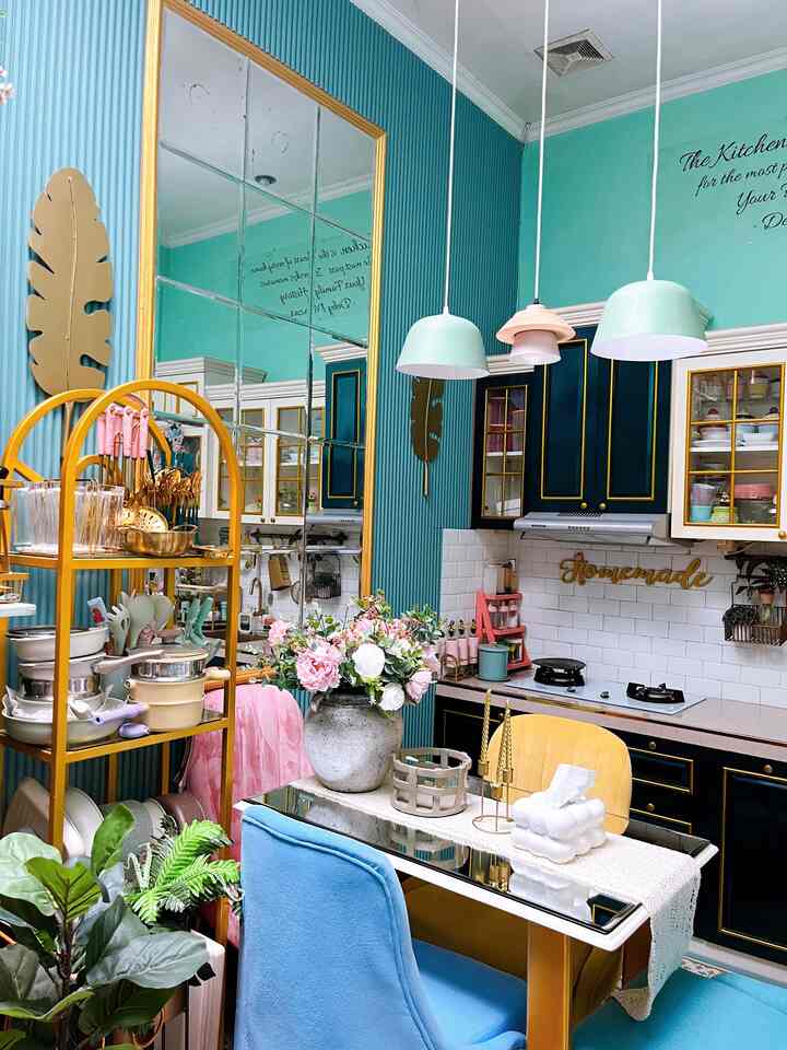 Teal-toned kitchen space featuring yellow storage rack and dining chairs arranged in a cozy retro style