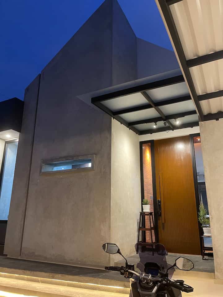 Kami paling suka dengan looks rumah ini pada malam hari. Aura maskulinnya nggak bakalan bosan untuk dipandang.

Kami juga menambahkan satu spot taman kering. Dengan satu tanaman Pakis Brazil, yang konon lekat dengan ciri khas rumah Industrial Minimalis. 

Area car port juga nggak terlalu besar, cukup untuk satu mobil dan dua motor saja. Kami juga menambahkan bench panjang untuk tempat duduk santai, jikalau ada tamu yang berkunjung dan ingin menikmati udara malam yang sejuk di rumah ini.


#RumahMinimalis #CatDinding #Cat #InspirasiCarPort #FasadRumah #FasadIndustrial #InspirasiRumahIndustrial #RumahDenganPekarangan #TamanKering 
