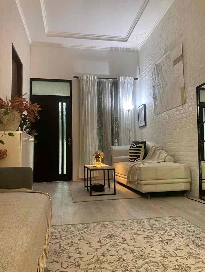 Monotone living room featuring white sofa, coffee table, wall decor, and curtains creating a simple and clean space