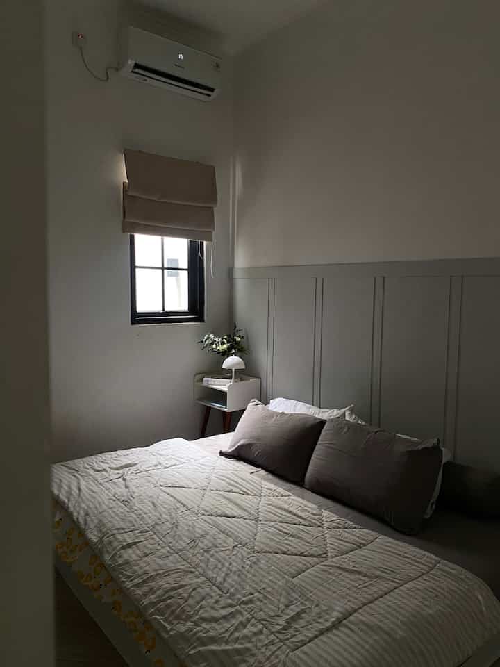 Minimal 4.5畳 bedroom with gray paneled wall and white ceiling, featuring comfortable bed with pillows and bedding