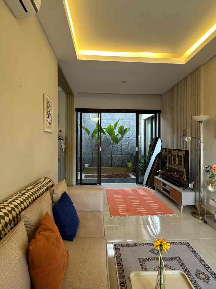 Beige and wood tone living room featuring a beige sofa and TV stand with natural ambiance