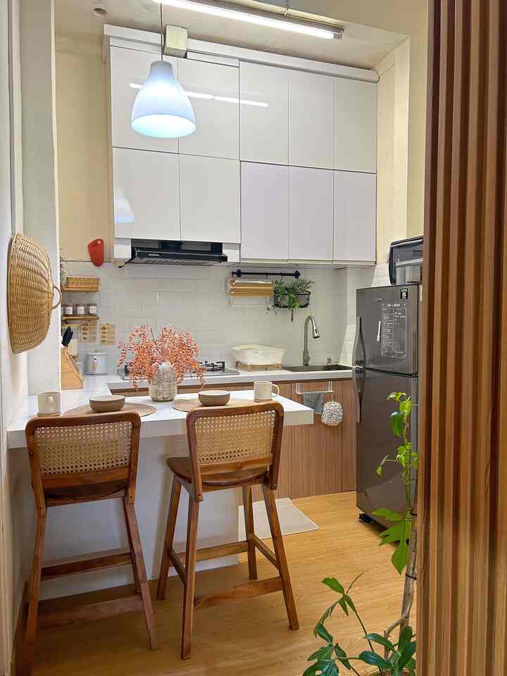 White and brown toned kitchen featuring bar stools and kitchen peninsula with placemats, creating a warm and tidy atmosphere
