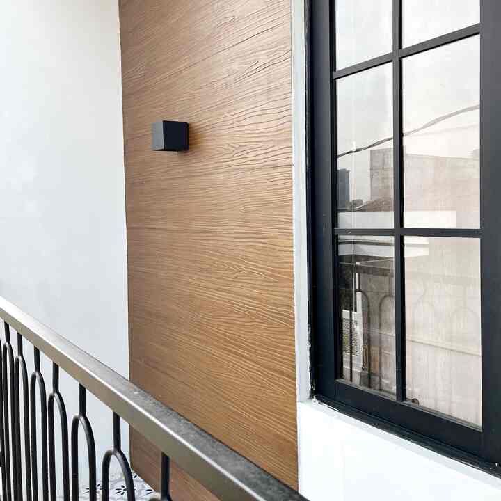 A balcony with wood tone and white walls featuring a black wall sconce, showcasing a clean outdoor space