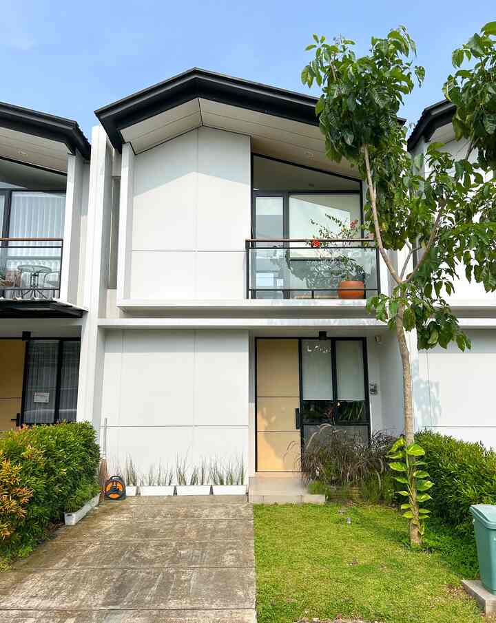 Modern house exterior with clean white walls and natural green garden featuring a second-floor balcony