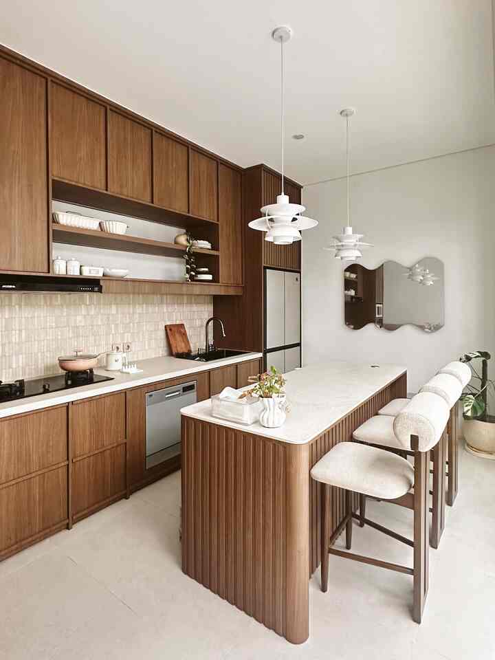 The heart of our home <3 

Ini adalah ruangan yang kami bangun pertama di rumah. Kami terinspirasi dari dapur ala scandinavian.

Ruangan dapur ini berukuran 6 x 3 M, memiliki island dan dining room yang menjadi satu membuat ruangan ini menjadi tempat berkumpul sambil menikmati hidangan ✨

Kabinet dan lemari berbahan multiplek lapis hpl dari Aica tertata rapi dari lantai hingga plafon untuk memaksimalkan ruangan penyimpanan, dipadukan dengan backsplash dari marmer menciptakan dapur ini terkesan semakin natural. 

Area island sengaja menggunakan permukaan warna terang, dengan detail kabinet warna walnut, menciptakan kesan elegan namun tetap homey. 

Bar stool yang terinspirasi dari pinterest kami pesan di pengrajin Jepara, @busrmebel. Dua lampu gantung bergaya scandinavian putih memberikan pencahayaan lembut di atas island, sementara cermin bentuk abstrak di dinding memperkaya dimensi ruangan.  

Semoga bisa menginspirasi yaa tetangga, detail ruangan lainnya bisa diliat di instagram @di.cirendeu ✨

#dapurmodern #inspirasirumah #stylerumah #makeoverdapur #stylingdapur #kitchenset #backsplashminimalis #dapurminimalis #dapursegaris #dapurimpian

