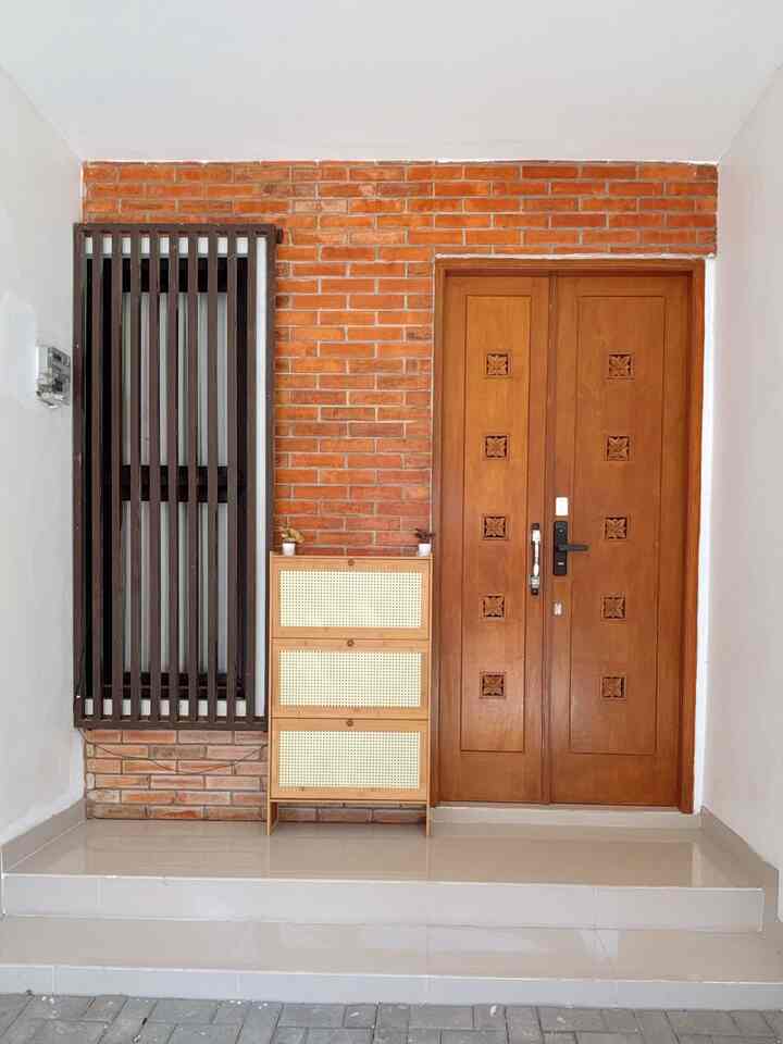 Orange and brown toned entrance featuring a brick wall and wooden shoe cabinet arranged neatly
