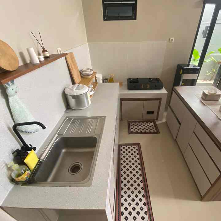 Rumah Kami mengusung konsep open-space, dimana ruang tamu, ruang makan, dan dapur, digabungkan menjadi satu area terbuka tanpa sekat dinding atau partisi. Kami memilih nuansa "earth tone" untuk menciptakan suasana dapur yang hangat dan modern. Permukaan meja dapur yang terbuat dari bahan cor dilapisi granit disandingkan dengan kitchen set custom berbahan multiplek dengan warna beige dan aksen kayu, menciptakan kesan bersih dan minimalis.

Di sebelahnya, terdapat meja makan (meja island) berbahan multiplek bertekstur alami, menyatu secara fungsional sebagai area makan atau coffee corner. Cahaya alami masuk lembut lewat bukaan kaca geser besar yang menghadap taman kecil, memberi kesegaran dan pencahayaan yang ideal sepanjang hari. Jendela horisontal kecil di atas dinding juga membantu sirkulasi udara tetap lancar.

Ruang ini menjadi tempat berkumpul favorit keluarga kecil kami, terasa lapang dan tenang, cocok untuk aktivitas memasak maupun bersantai bersama keluarga dengan gaya simpel namun estetis.

#dapurminimalis #dapursegaris #mejamakanminimalis #kitchenset #kitchensetminimalis #tableisland #makeoverdapur #stylingdapur #dapurimpian
