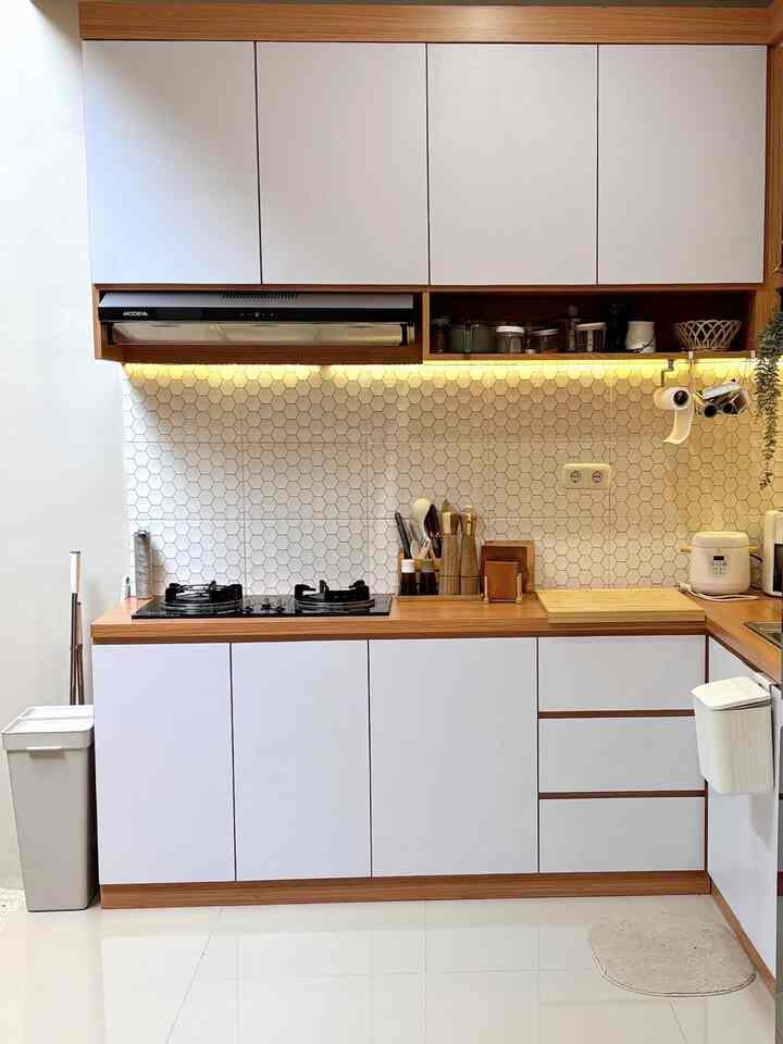 White and wood tone compact kitchen featuring clean storage and kitchen tools with a bright, organized atmosphere