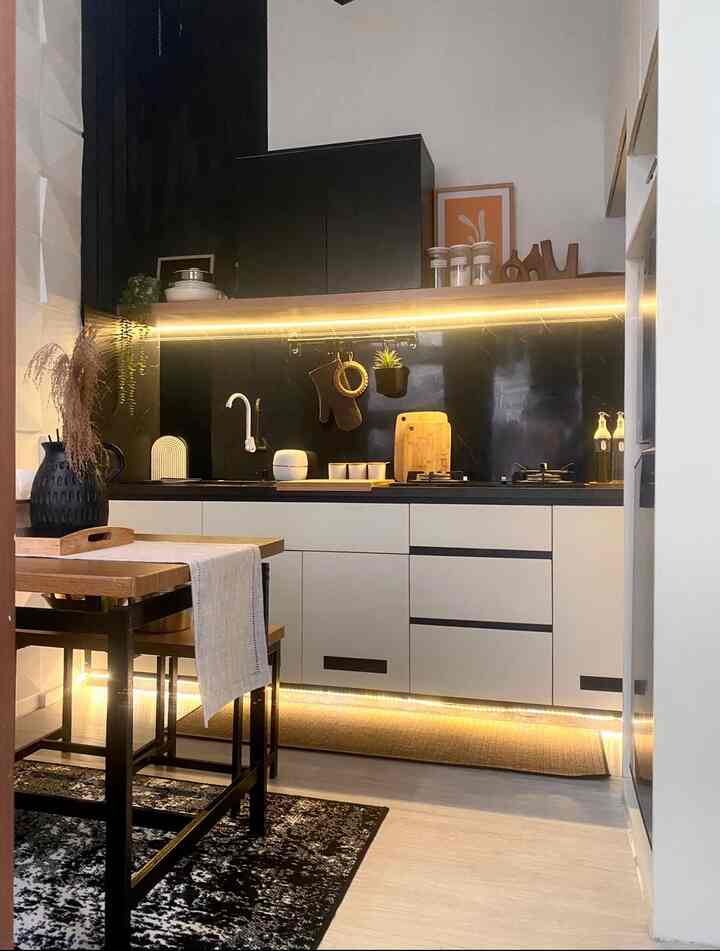Modern kitchen in black and white tones, featuring wood dining table with table runner and warm LED lighting