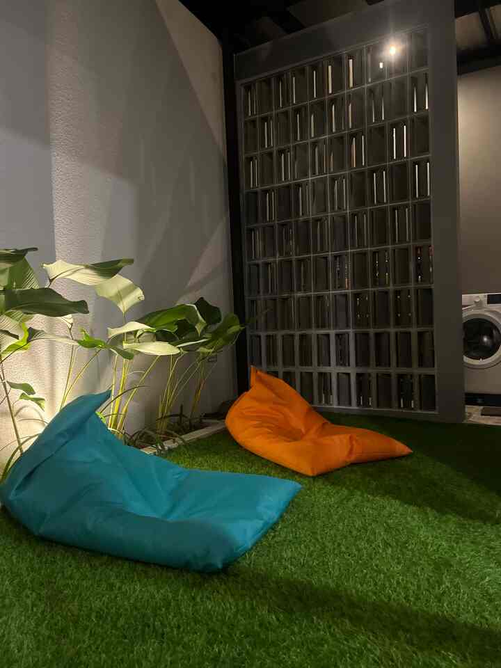 Industrial style terrace with green synthetic grass carpet, featuring two bean bags and plants creating a cozy outdoor area