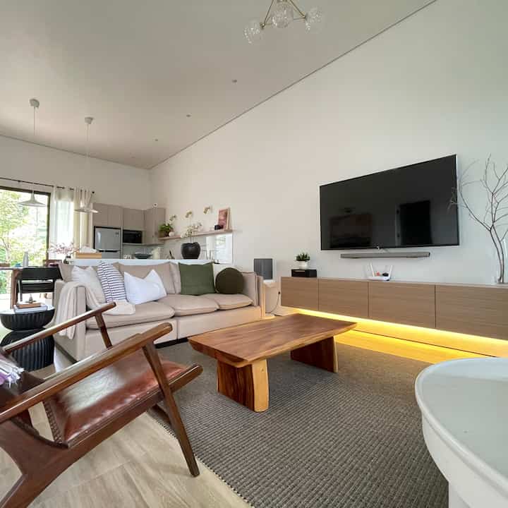 Minimal living room with white and wood tones, featuring a comfortable sofa and wooden coffee table in a natural setting