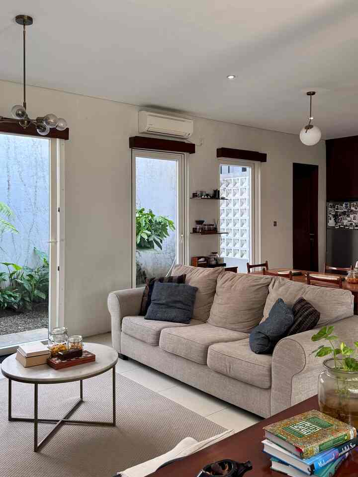 Bright white-toned living and dining area with beige sofa, large windows bringing in ample natural light