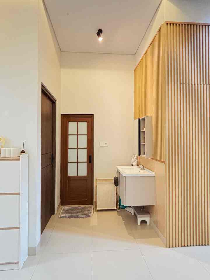 A small bathroom space featuring wood tone wall panel and white cabinet set creating a natural modern look