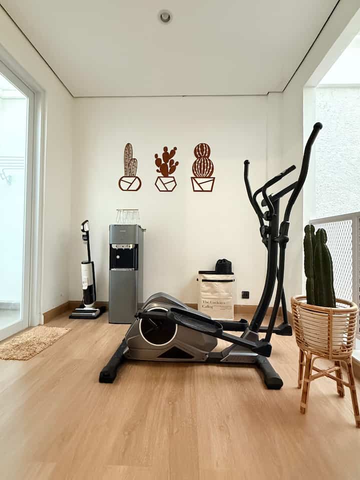 Ini area selasar di lantai 2 yang juga dimaksimalkan jadi mini gym rumahan. Dekorasinya minimalis dan diutaman ke elemen fungsional yang ada sense dekoratif supaya nyambung sama keseluruhan desain rumah. Nah, kalau mau bikin sudut olahraga di rumah yang tetap cantik, ini dia beberapa tipsnya:

1. Pilih lantai yang mendukung look & fungsi
Lantai SPC bermotif kayu seperti ini nggak cuma praktis (tahan beban alat berat, nggak licin), tapi juga bikin ruangan terasa hangat dan menyatu dengan tema interior.

2. Gunakan dekor dinding simpel tapi eye-catching. Wall decor tipis seperti potongan triplek berbentuk kaktus bikin dinding nggak terlihat kosong, tetap ada aksen visual tanpa bikin suasana terlalu ramai.

3. Tambahkan elemen natural
Cukup tambahkan satu-dua tanaman hias dengan pot rotan atau pot natural lain yang memberi tekstur organik, biar area terasa lebih hidup dan segar.

4. Manfaatkan storage yang juga dekoratif
Pilih storage atau keranjang yang punya desain clean, misalnya canvas bag bergaya minimalis, supaya tetap enak dilihat meski fungsinya untuk menyimpan perlengkapan olahraga.

5. Jaga space tetap lapang
Atur alat olahraga, dispenser, atau perabot lain supaya nggak menumpuk, biar area mini gym tetap lega, clean, dan enak dilihat.

#MiniGym #HomeGymIdeas #MiniGymRumahan #DekorasiRumah #SelasarCantik #SPCLantai #RumahMinimalis #HomeDecorTips #GymAtHome #SudutRumahEstetik #DekorasiFungsional #WallDecor #YogaOrganizerBox