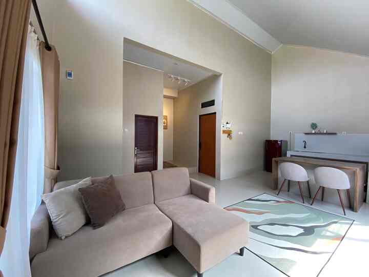 Beige and white toned living room featuring a beige sectional sofa and colorful carpet with natural modern style