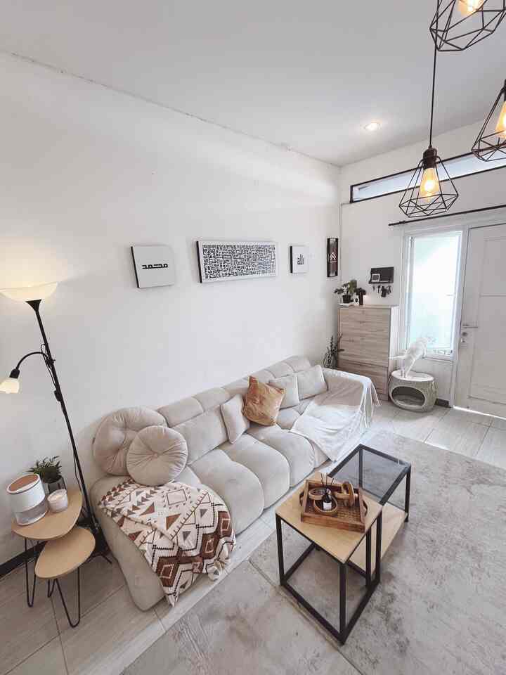Bright white-toned living room featuring a modern sofa and carpet with cozy interior atmosphere