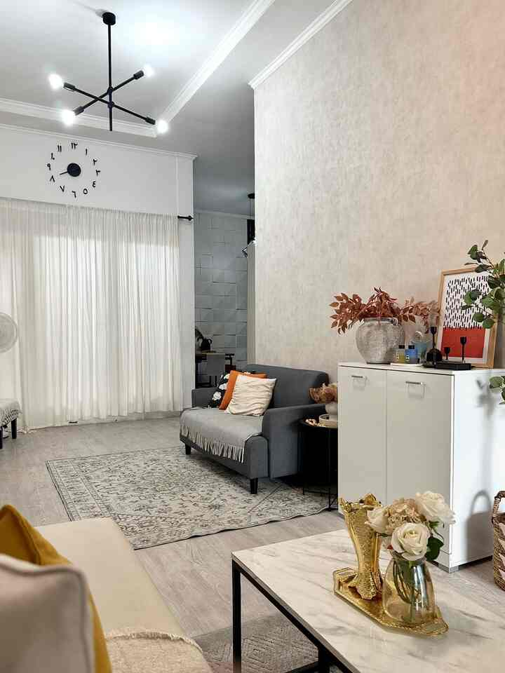 Natural modern living room with beige wall and black ceiling light, featuring gray sofa and marble coffee table in a cozy space