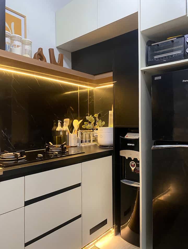 Black and white toned kitchen featuring a gas stove, refrigerator, and neatly arranged kitchen utensils with a modern atmosphere