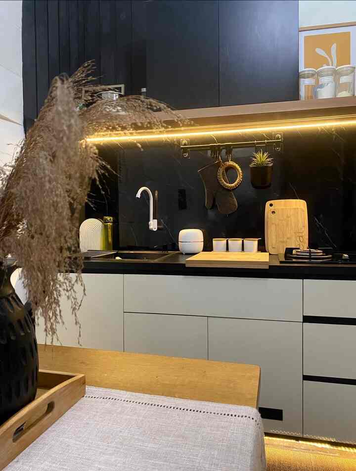 Modern kitchen with black cabinetry and natural wood tones, featuring a wooden table with table runner and stylish storage ideas