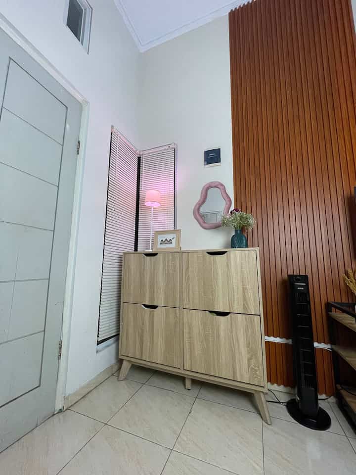 Sudut kecil ini jadi tempat pertama yang kami lewati setiap kali pulang ke rumah.
Walau sempit, area dekat pintu tetap aku fungsikan semaksimal mungkin, ada rak sepatu kayu supaya alas kaki nggak berserakan, dan ada cermin unik berbingkai pink clay-look buat sekadar cek penampilan sebelum berangkat.

Lampu berdiri dengan cahaya lembut di pojok ruangan juga jadi detail kecil yang bikin suasana entryway tetap hangat dan welcoming.
Nggak perlu ruang besar, yang penting niat menata dan fungsinya tepat. Anak-anak pun jadi terbiasa meletakkan sepatu di tempatnya.

Karena buatku, rumah kecil bukan soal sempit atau luas, tapi tentang bagaimana tiap sudutnya bisa mendukung keseharian dengan nyaman.

#RakSepatuKayu
#CerminDekoratif
#LampuLantai
#PanelDindingKayu
#BlindJendelaMinimalis
#KeramikLantaiGlossy
#CatDindingNetral
#HandlePintuMinimalis
#Entryway
#SmallEntrance