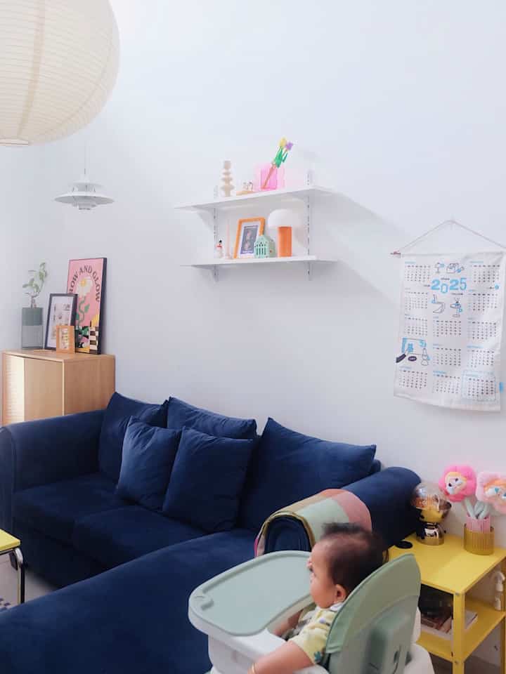 White-toned living room featuring a navy sofa and baby high chair, creating a cozy family space