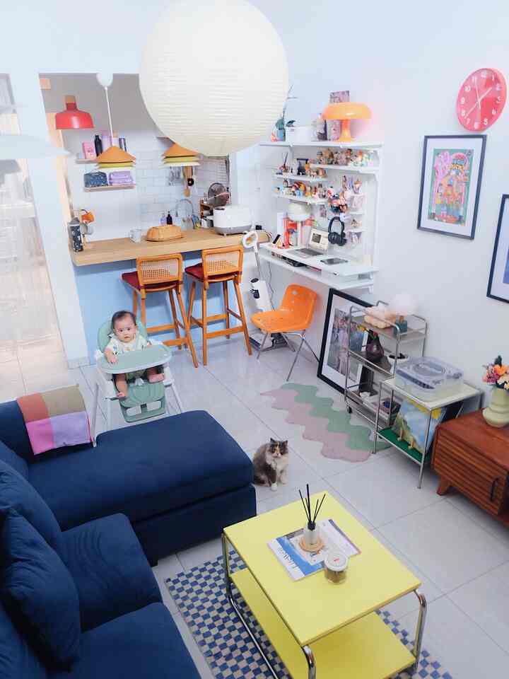 Mid-century modern living room and open kitchen space featuring a blue sofa, yellow coffee table, with a baby and cat present