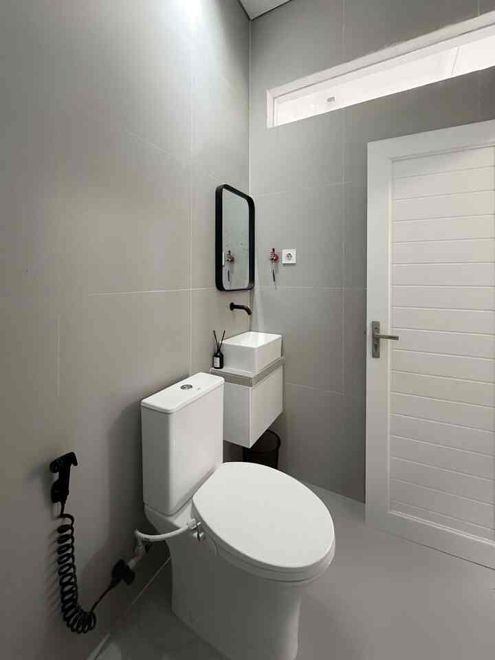 White and gray toned bathroom featuring a toilet and sink with a clean, simple design
