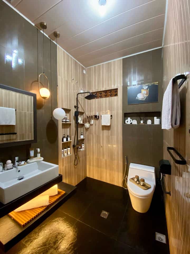 Have a bathroom like a hotel bathroom? Why not! 
With an area of 2.5 X 1.8 meters, you can have your dream bathroom. I designed this bathroom myself according to my needs. I deliberately chose non-fiber wall tiles so that they are easy to clean and for the floor tiles I chose fiber granite so that they are not slippery and comfortable of course. For the material, I made sure it was the best but still pocket-friendly, because this bathroom was certainly made for the long term. Now for this one, this Vanity area is what I pay the most attention to. The height of the sink is adjusted to the height of my body, so it won't be too high or too low. Can you imagine if I just want to wash my hands, my hands will get sore because of the height? And then, there is wall storage for my skincare so that I am more diligent in doing skincare and more glowing 😅. Then one more thing, under the sink there is open storage with warm LED lighting accents to make it more cozy. They say, if you want to know if someone is clean or not, try looking at their bathroom. Is that true??? 
#BathroomCeramics #DindingKamarMandi #KeramikLantai #wastafel #wastafelKamarMandi #Jershower #Closet #GantunganHanduk #TempatTisu #kabinetcermin #LampuGantung #HandleKamarMandi #PintuKamarmandi #PintuAlumuniumKamarMandi #FloorDrain #SaringanGotKamarMandi #ShowerColumnSet #RenovasiKamarMandi #BathroomMakeOver #InspirasiKamarMandi