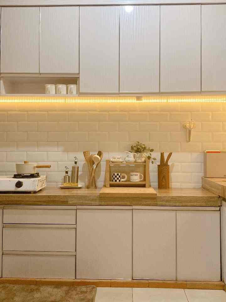 Warm-toned kitchen featuring wood countertops and white cabinets with organized kitchen utensils and soft lighting
